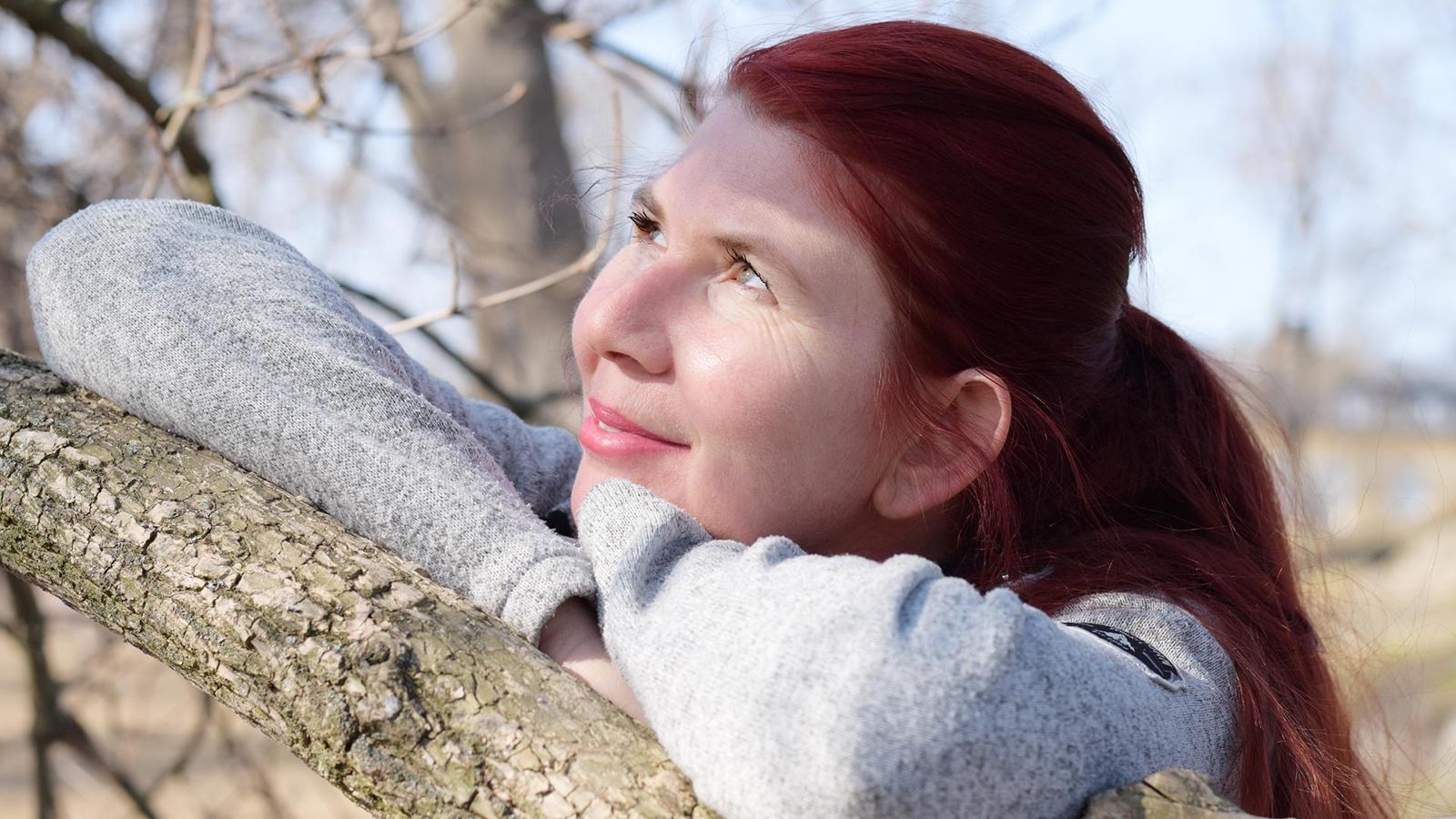 Victorita Necula står i solen vid ett träd med blicken riktad upp i himlen