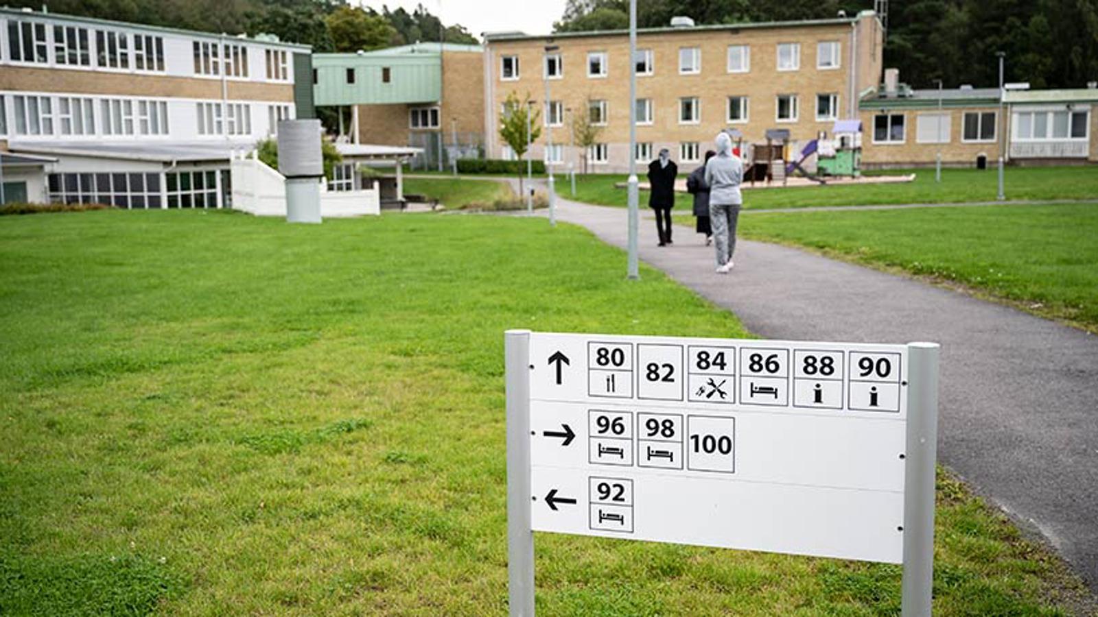 Området vid Migrationsverket Sagåsen i Kållered. På området syns tre personer som går på en väg mot byggnaden.