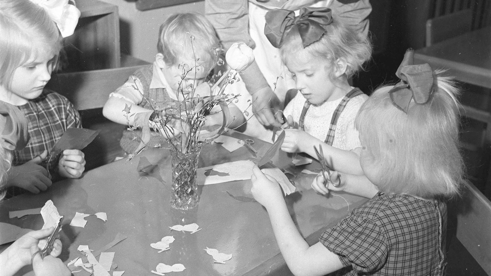 Några barn sitter kring ett bord och pysslar, året är runt 1950.
