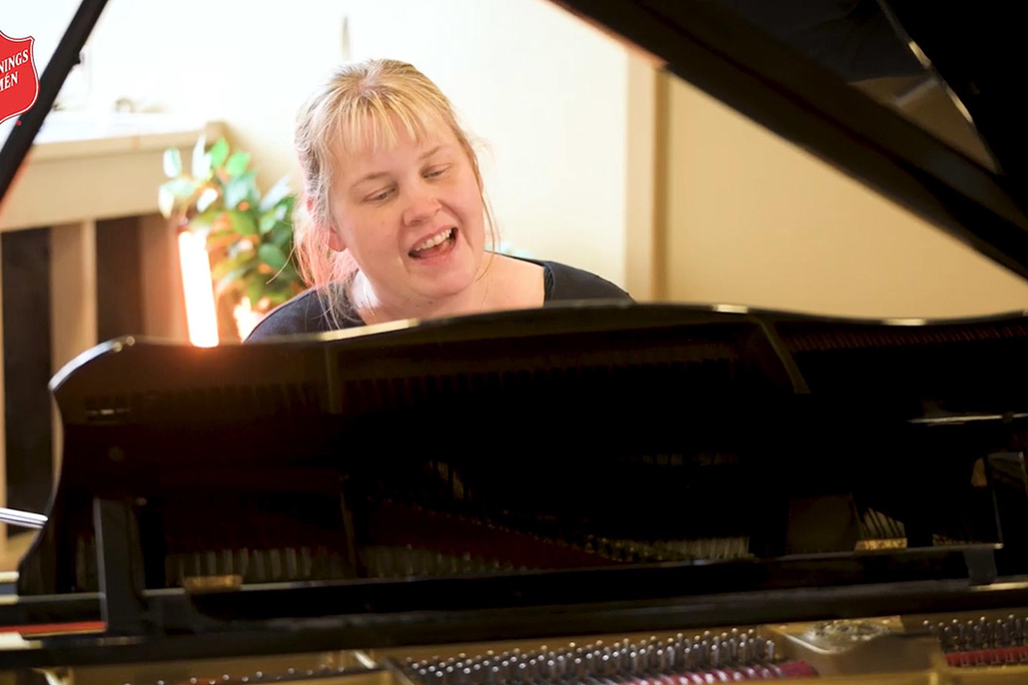 Elisabeth Grahn sitter vid ett piano och spelar och sjunger.