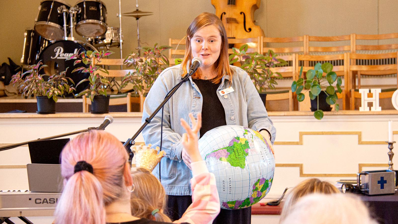 Lina håller i en uppblåsbar jordglob under sin predikan för barn och vuxna på Frälsningsarmén i Eksjö.