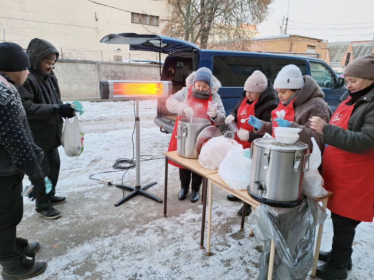 Frälsningsarméns volontärer delar ut varm mat till människor utomhus i vinterkyla i Ukraina.