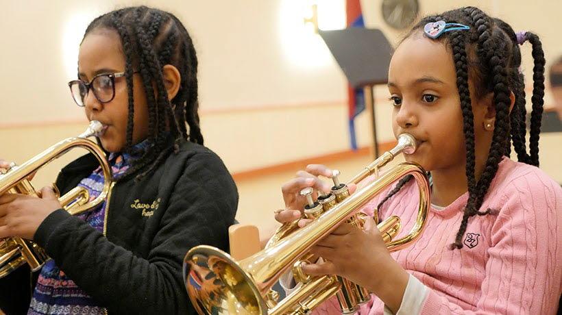 Två flickor på musikkollo som sitter och spelar trumpet.