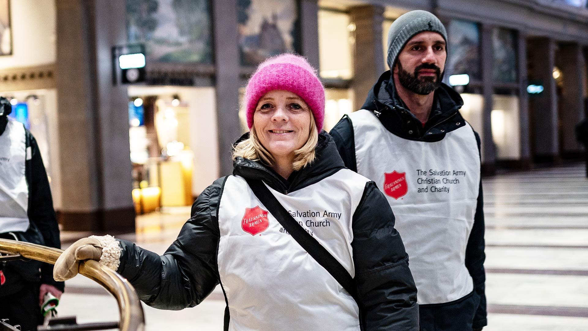 Jenny Alm och Julian de Acha ute på Stockholms central - iklädda västar med Frälsningsarméns sköld på
