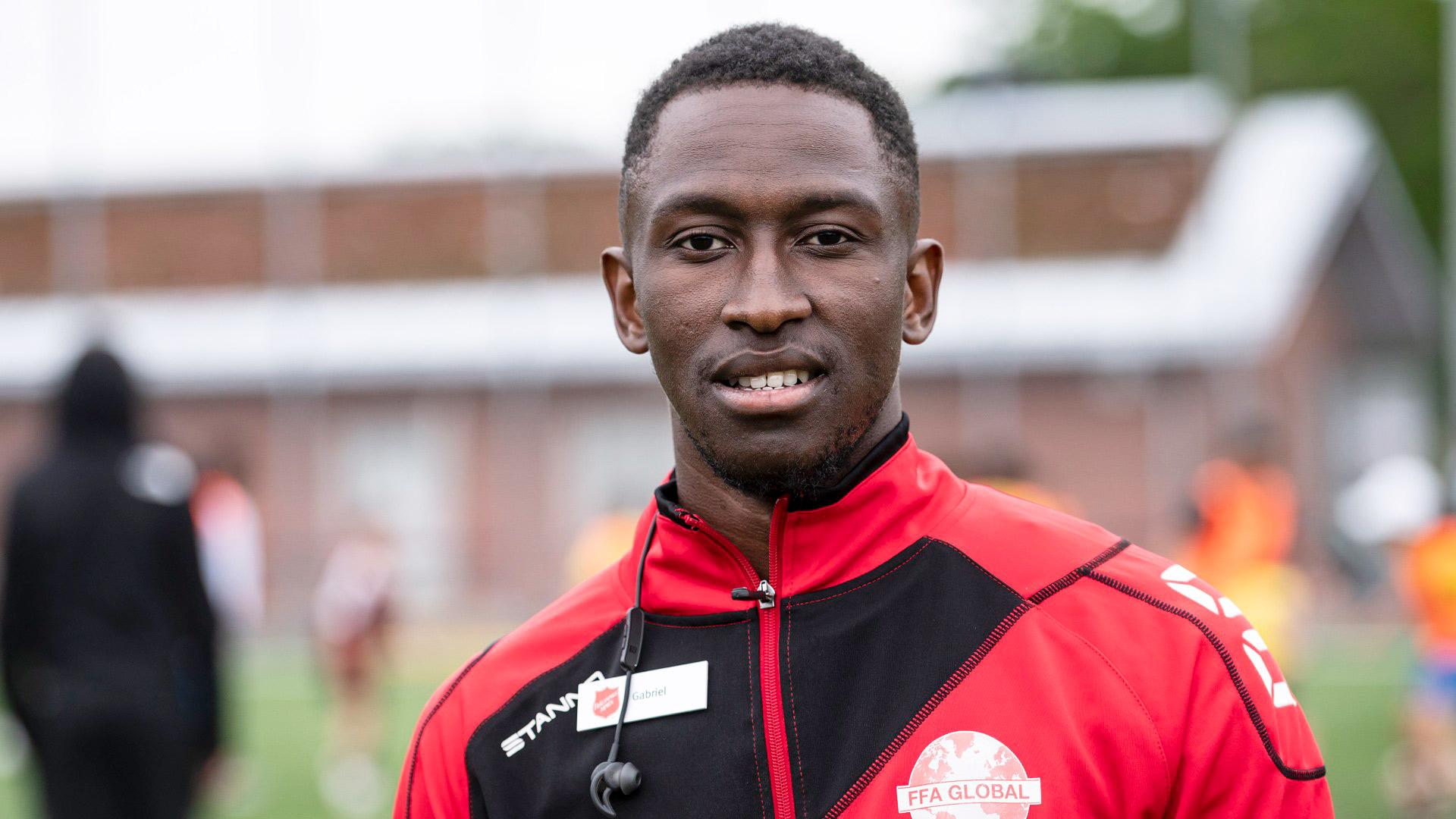 Gabriel Thsidimu med en fotbollsplan i bakgrunden.