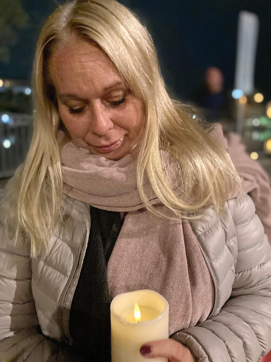 Vinterklädda volontären Ulrika håller i ett tänt stearinljus