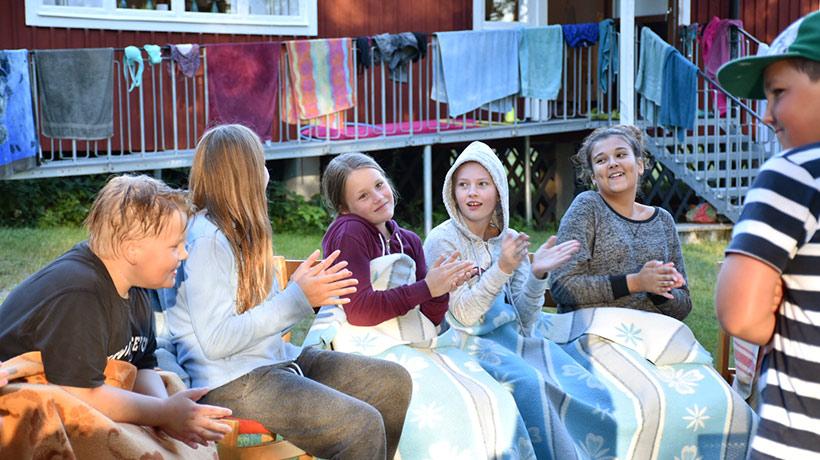 Ett gäng glada barn som sitter och klappar händerna.