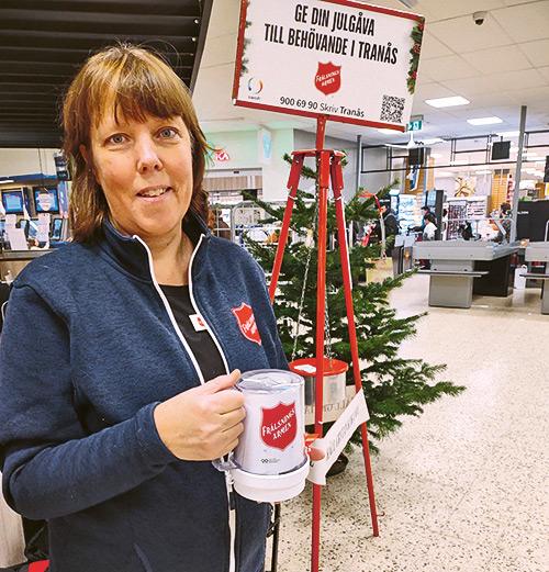 Kvinna står med en insamlingsbössa vid en julgryta inne i en butik