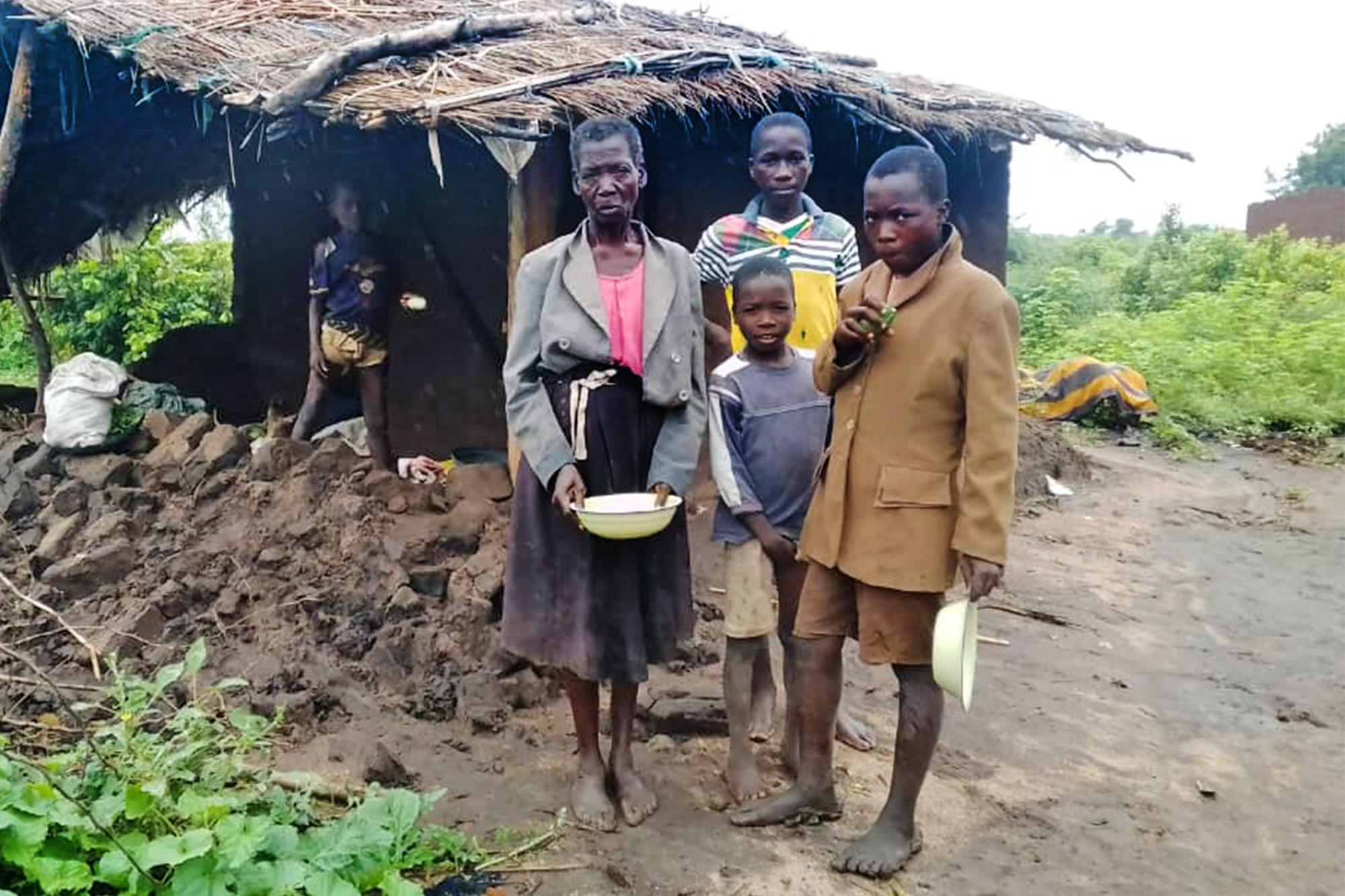 En familj i Malawi står utanför en hydda som har blivit förstörd av cyklonen.