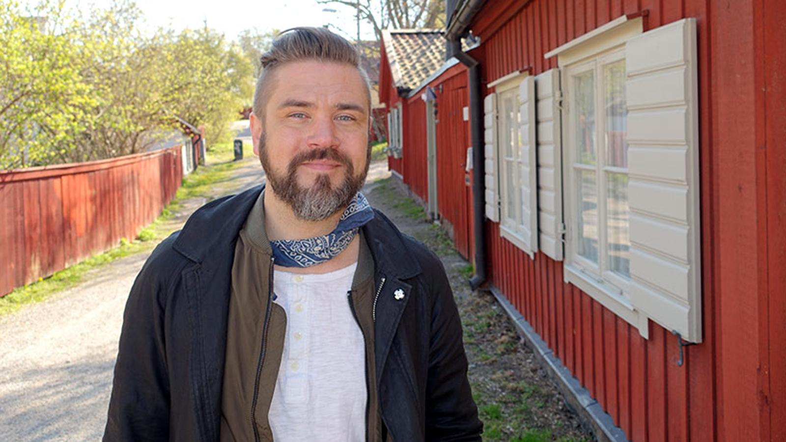 Linus Fagerström som står på en grusväg. Till höger om honom står det röda hus.