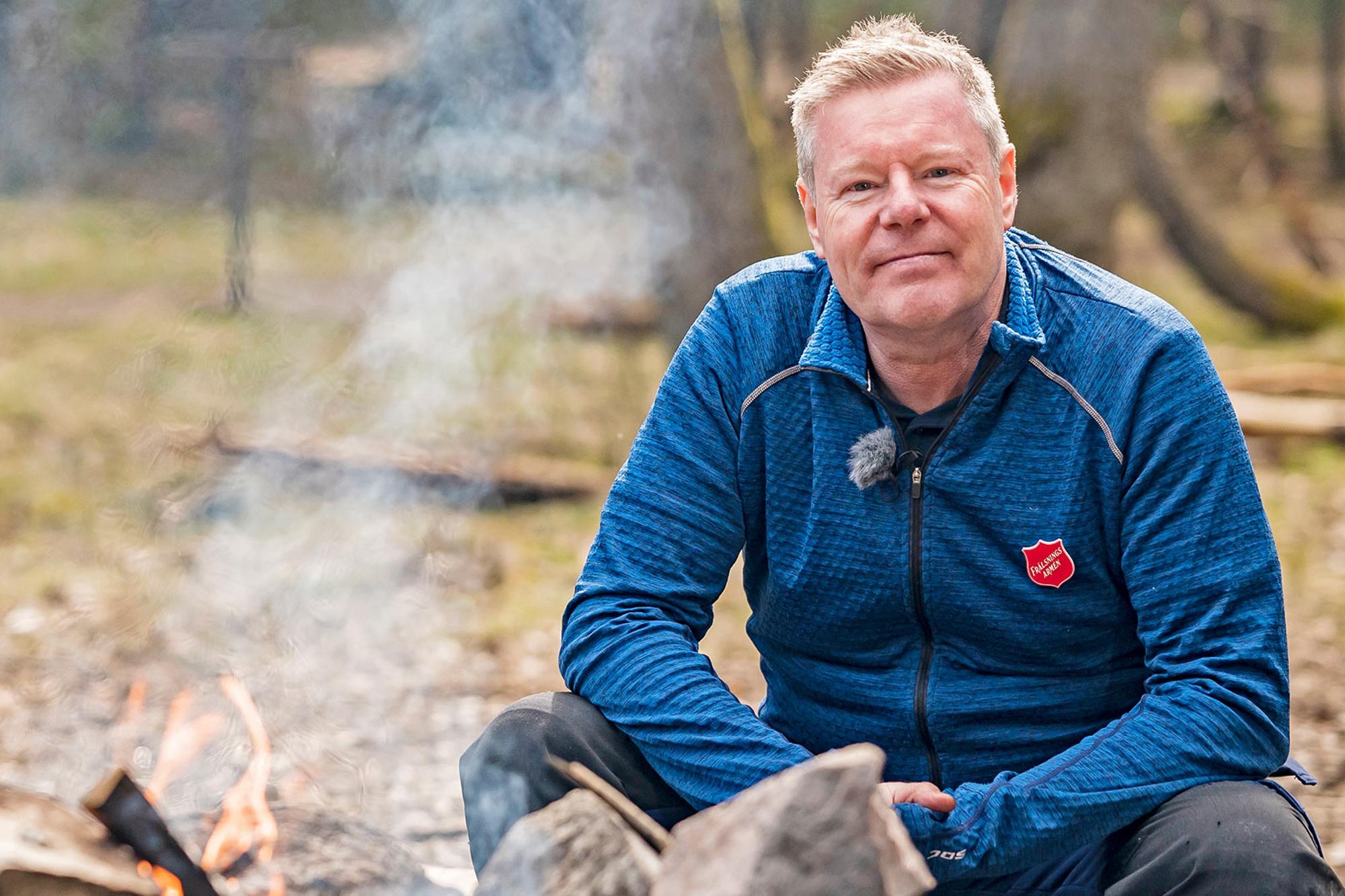 Överste Bo Jeppsson, Frälsningsarméns ledare i Sverige och Lettland sitter vid en brinnande eld på en rastplats i skogen.