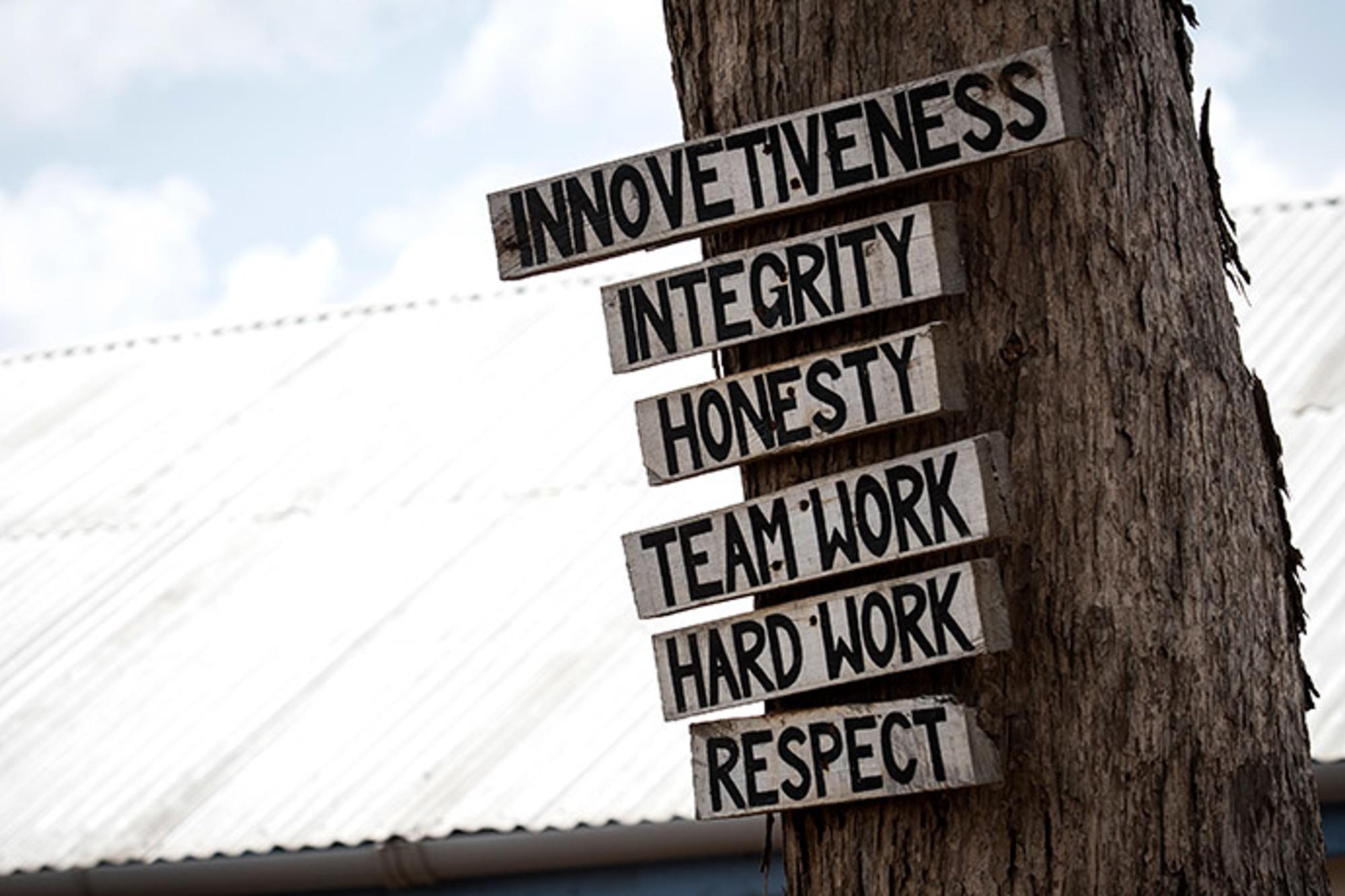 6 skyltar, med olika ord, som sitter på ett träd. På skyltarna står det "Innovetiveness", "Integrity", "Honesty", "Teamwork", "Hard work" och "Respect".