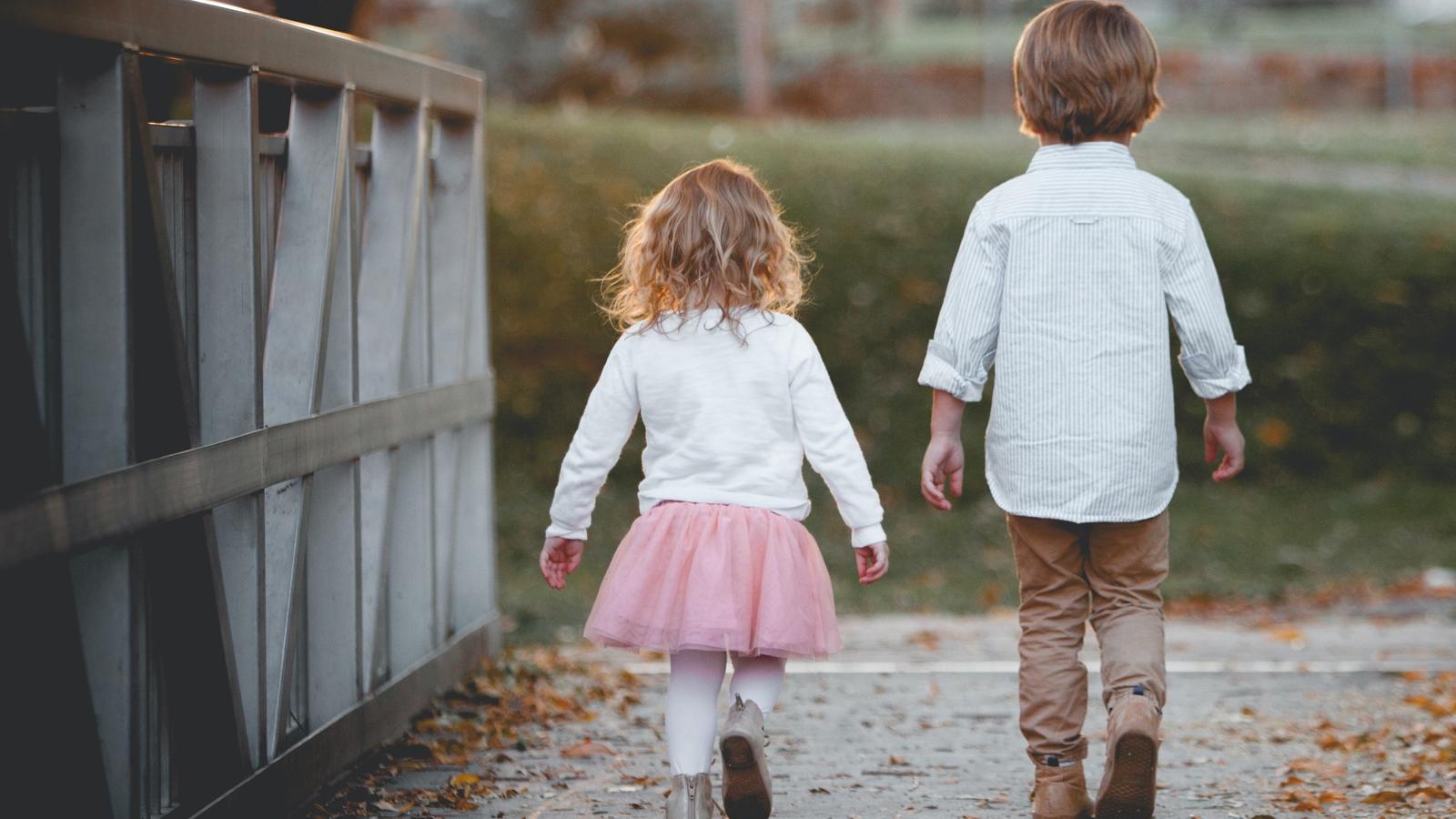 Två små barn som går bredvid varandra på en bro.