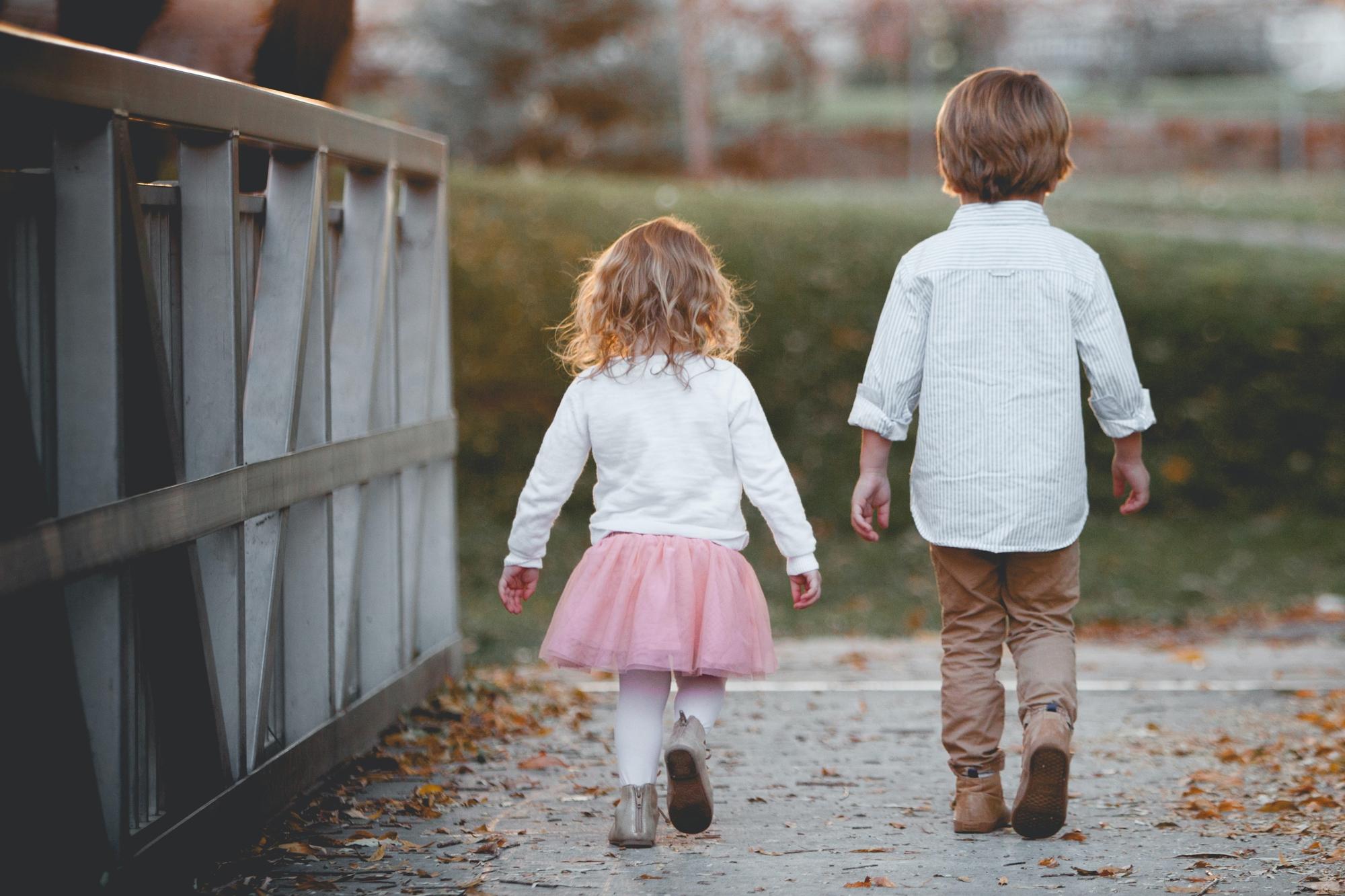 Två små barn som går bredvid varandra på en bro.