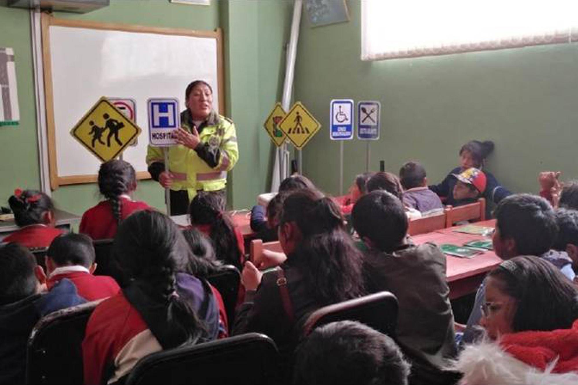 Barn i Bolivia sitter i ett klassrum- framför dem står en person och undervisar.