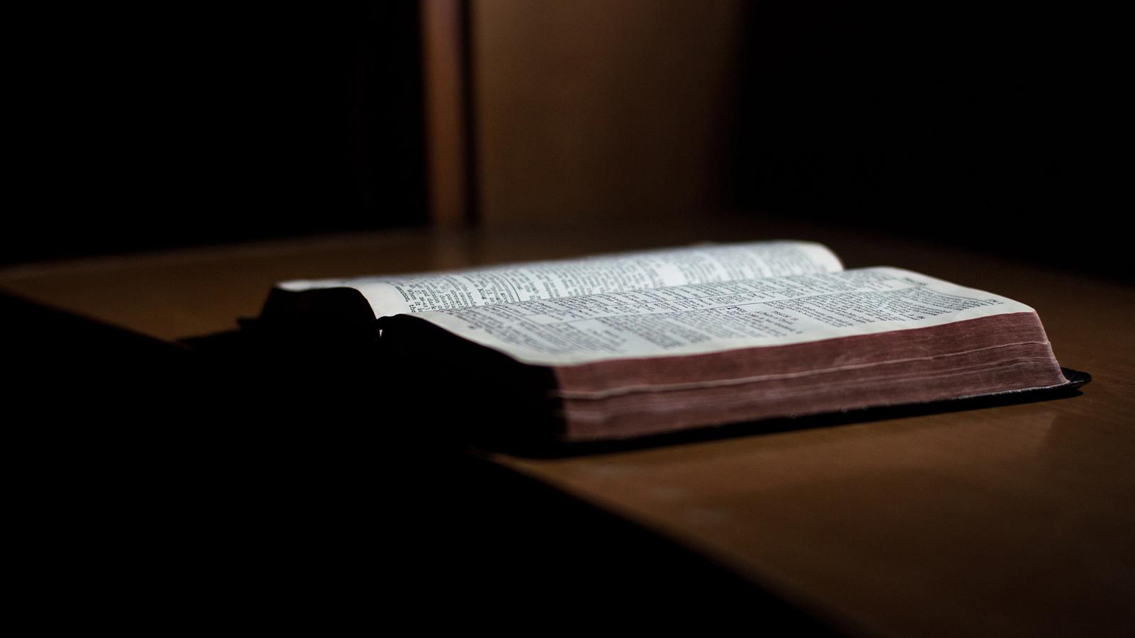 En uppslagen bibel liggandes på ett bord