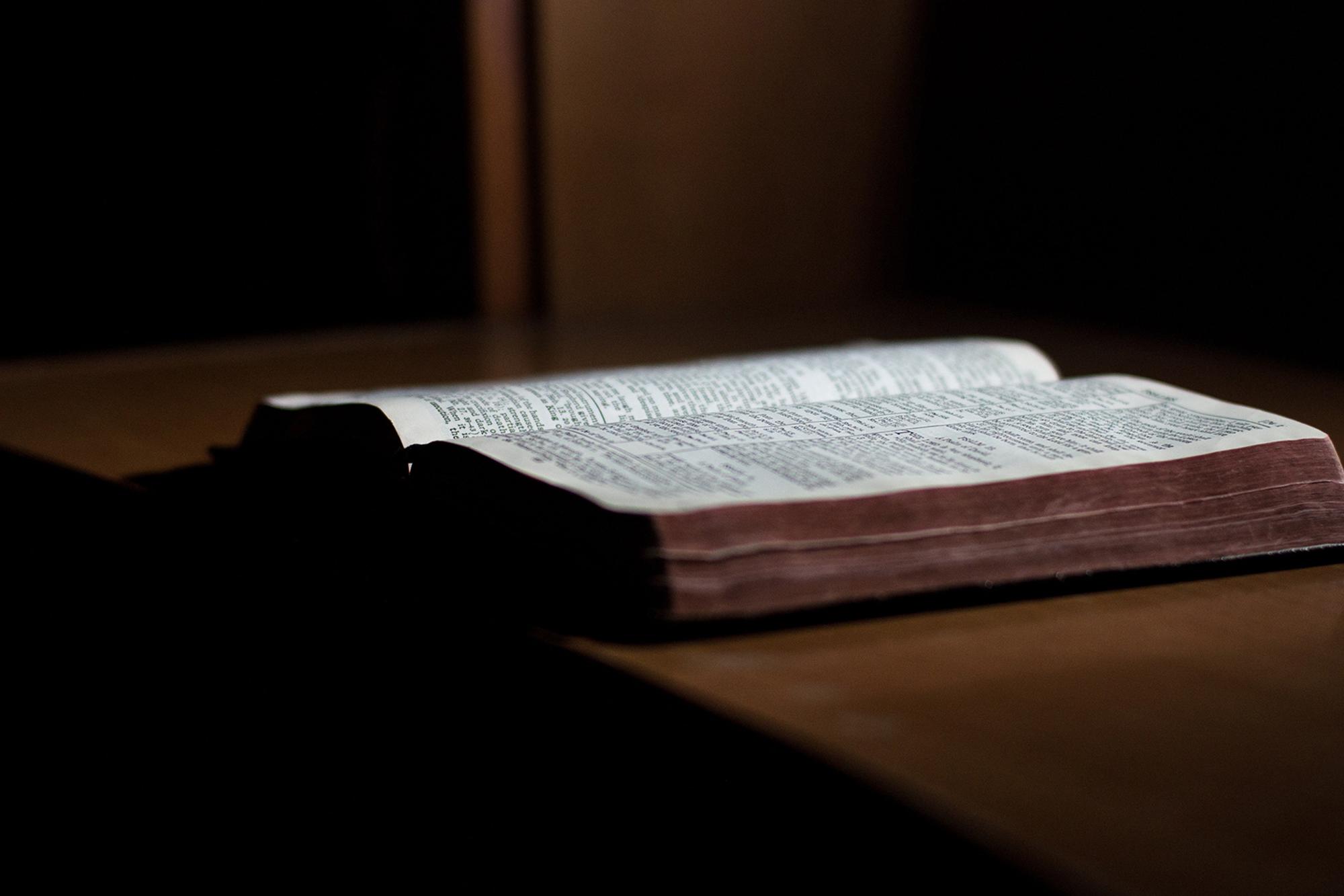 En uppslagen bibel liggandes på ett bord