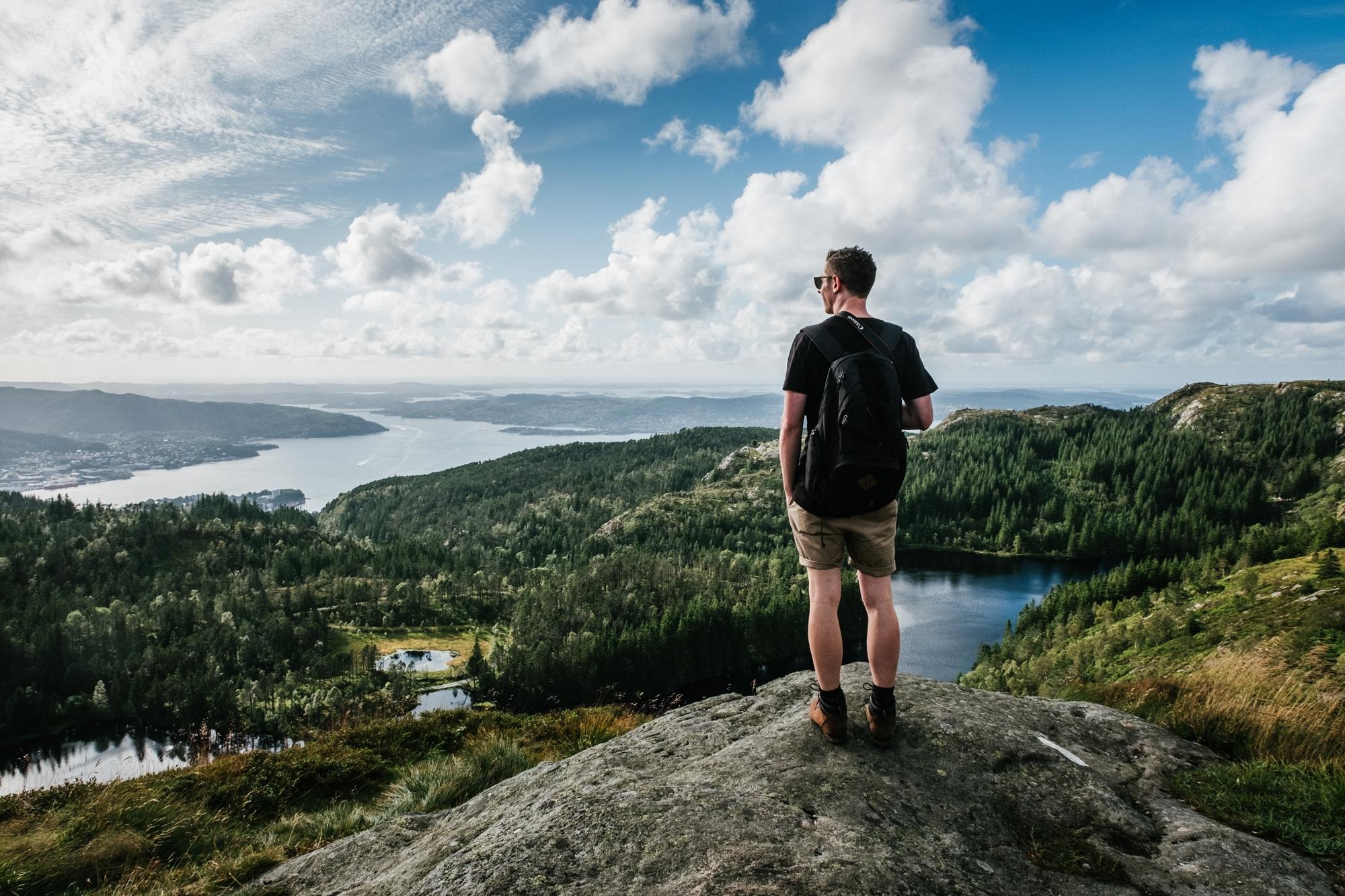Ryggtavlan på en man som står på ett berg och tittar ut mot naturen.