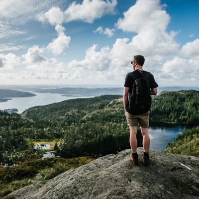 Ryggtavlan på en man som står på ett berg och tittar ut mot naturen.