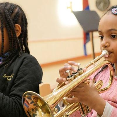 Två flickor på musikkollo som sitter och spelar trumpet.