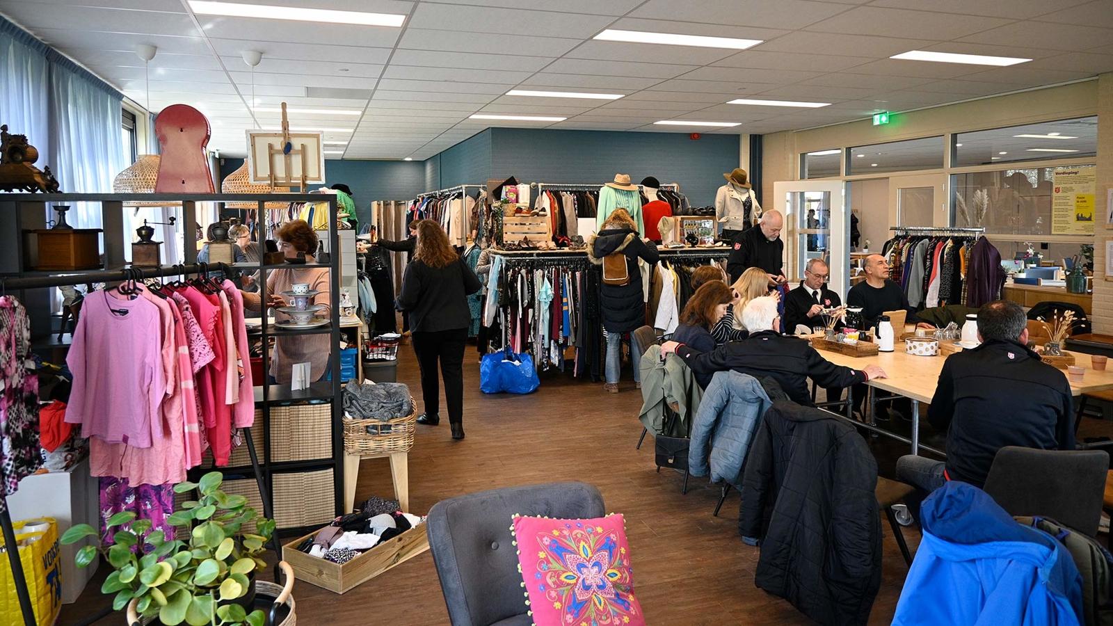 Second hand-butiken i Frälsningsarméns fastighet i Almere. I butikens kafé- och samtalsdel sitter det personer runt ett bord som fikar.