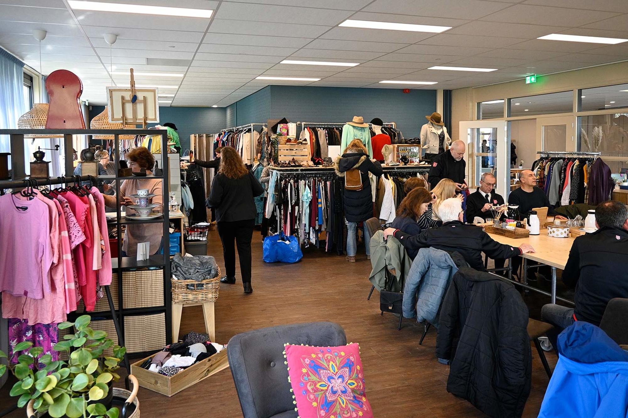 Second hand-butiken i Frälsningsarméns fastighet i Almere. I butikens kafé- och samtalsdel sitter det personer runt ett bord som fikar.