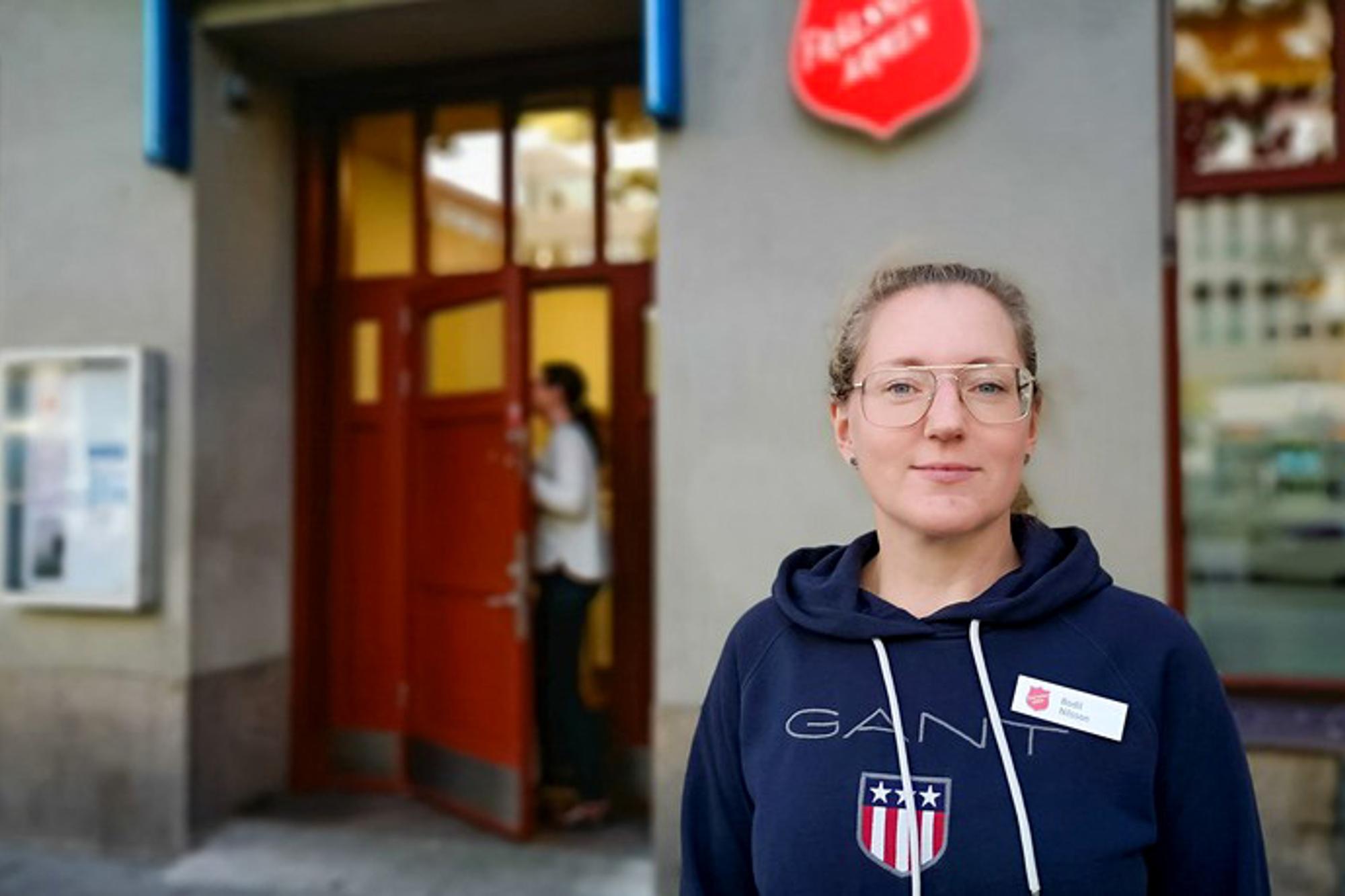 Bodil Nilsson, verksamhetschef för Frälsningsarméns sociala center i Stockholm. Hon står vid centrets entré och tittar in i kameran.