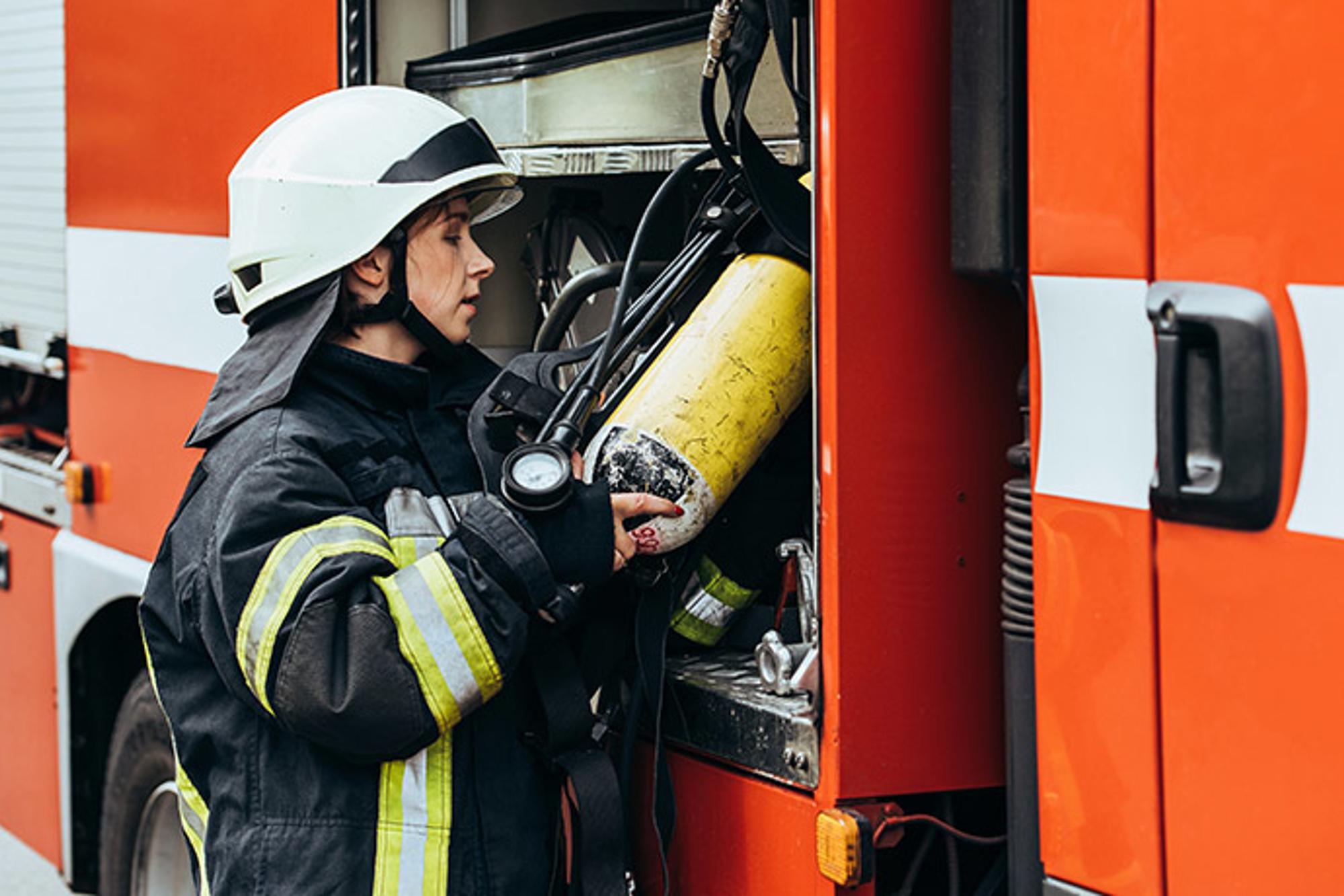 En kvinna i branduniform som står vid en brandbil.