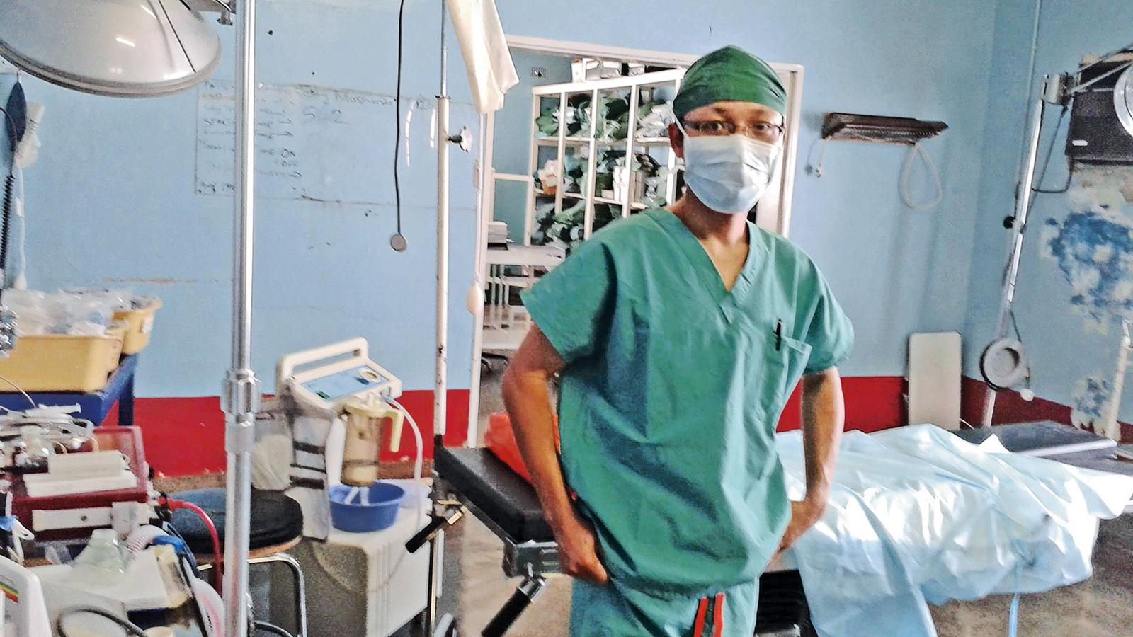 En läkare i Zimbabwe står i ett rum fullt med vårdmaterial och en vårdsäng. 