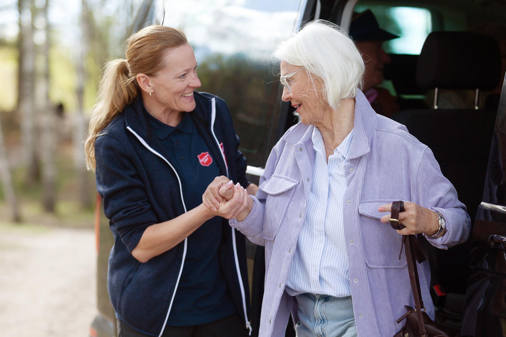 En kvinna från Frälsningsarmén som hjälper en pensionär ut ur en bil.