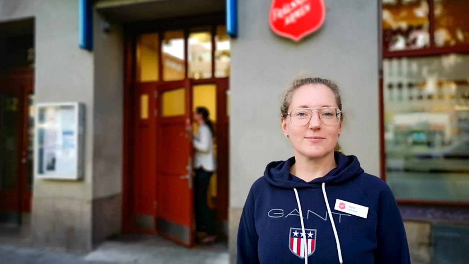 Bodil Nilsson, verksamhetschef för Frälsningsarméns sociala center i Stockholm. Hon står vid centrets entré och tittar in i kameran.