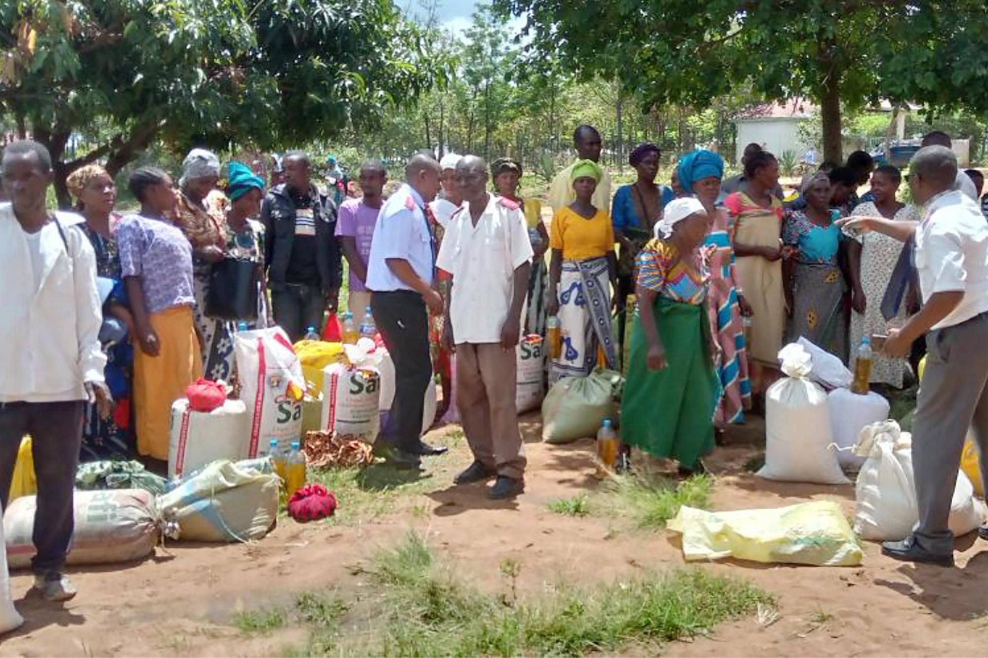 Frälsningsarméns personal i Tanzania delar ut mat från säckar till en grupp människor.