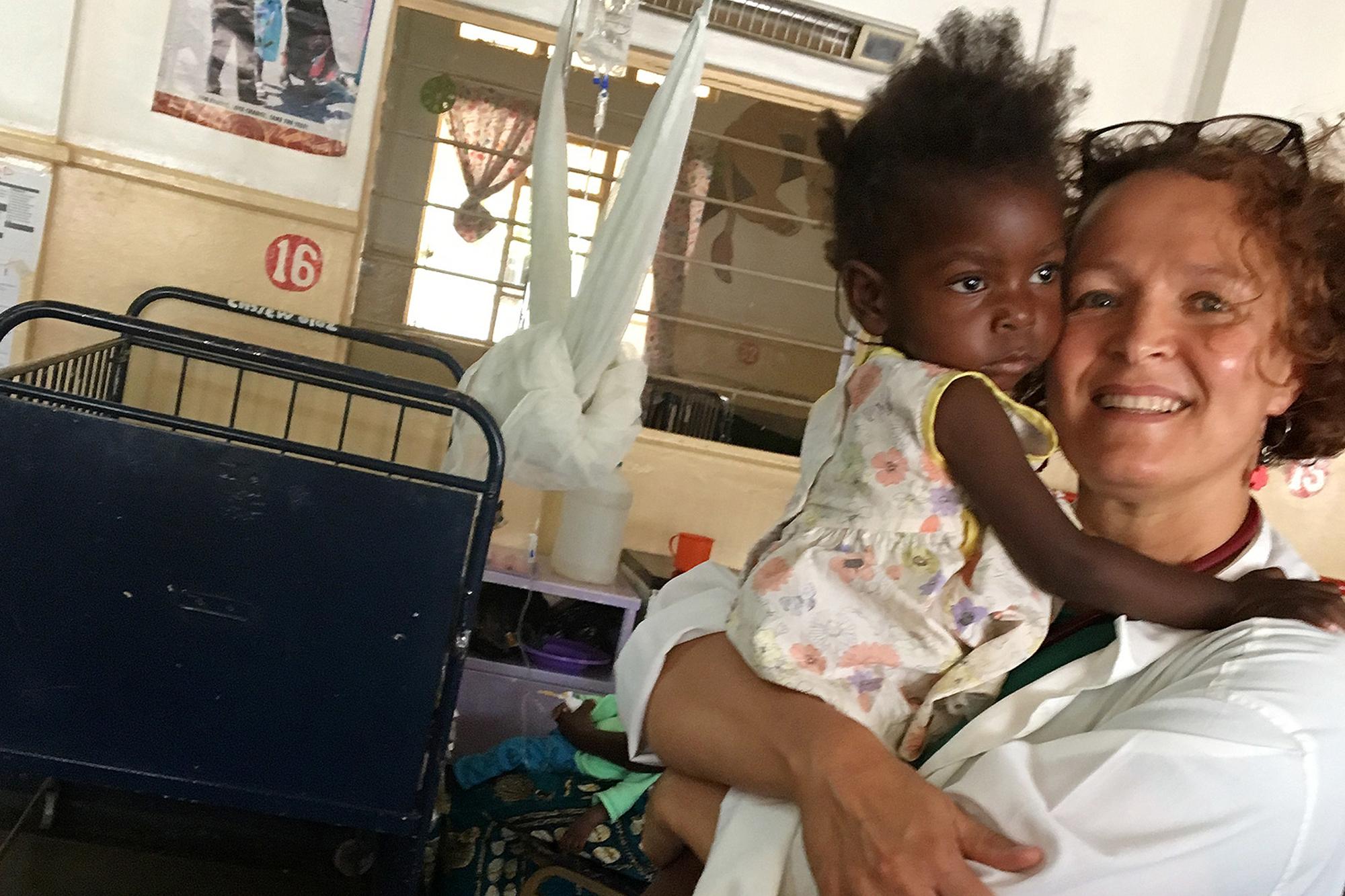 Elsa Björkqvist i ett vårdrum i zambia, i famnen håller hon i ett litet barn.