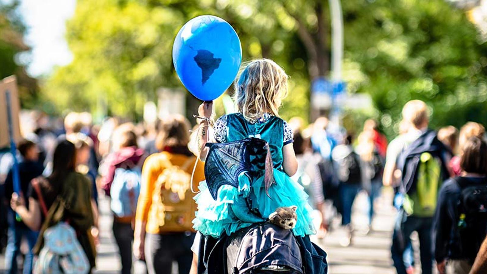 Ryggtavlan på ett barn som håller i en blå ballong.
