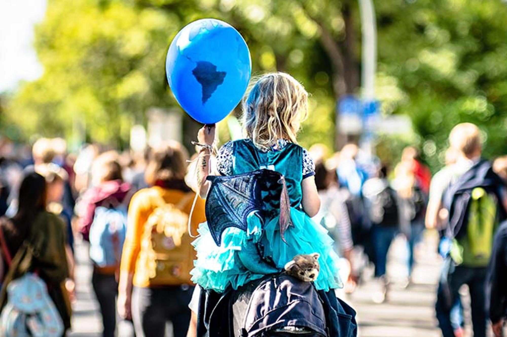 Ryggtavlan på ett barn som håller i en blå ballong.