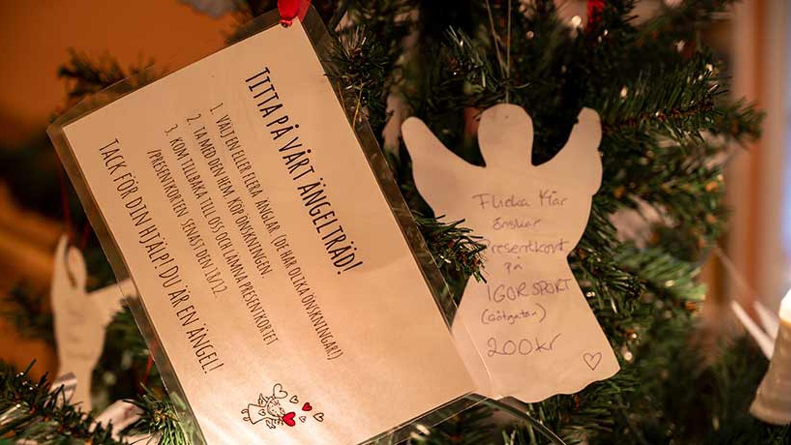 En julgran med ängelkort med text: "Flicka 14 år önskar presentkort på IGOR SPORT 200 kr".