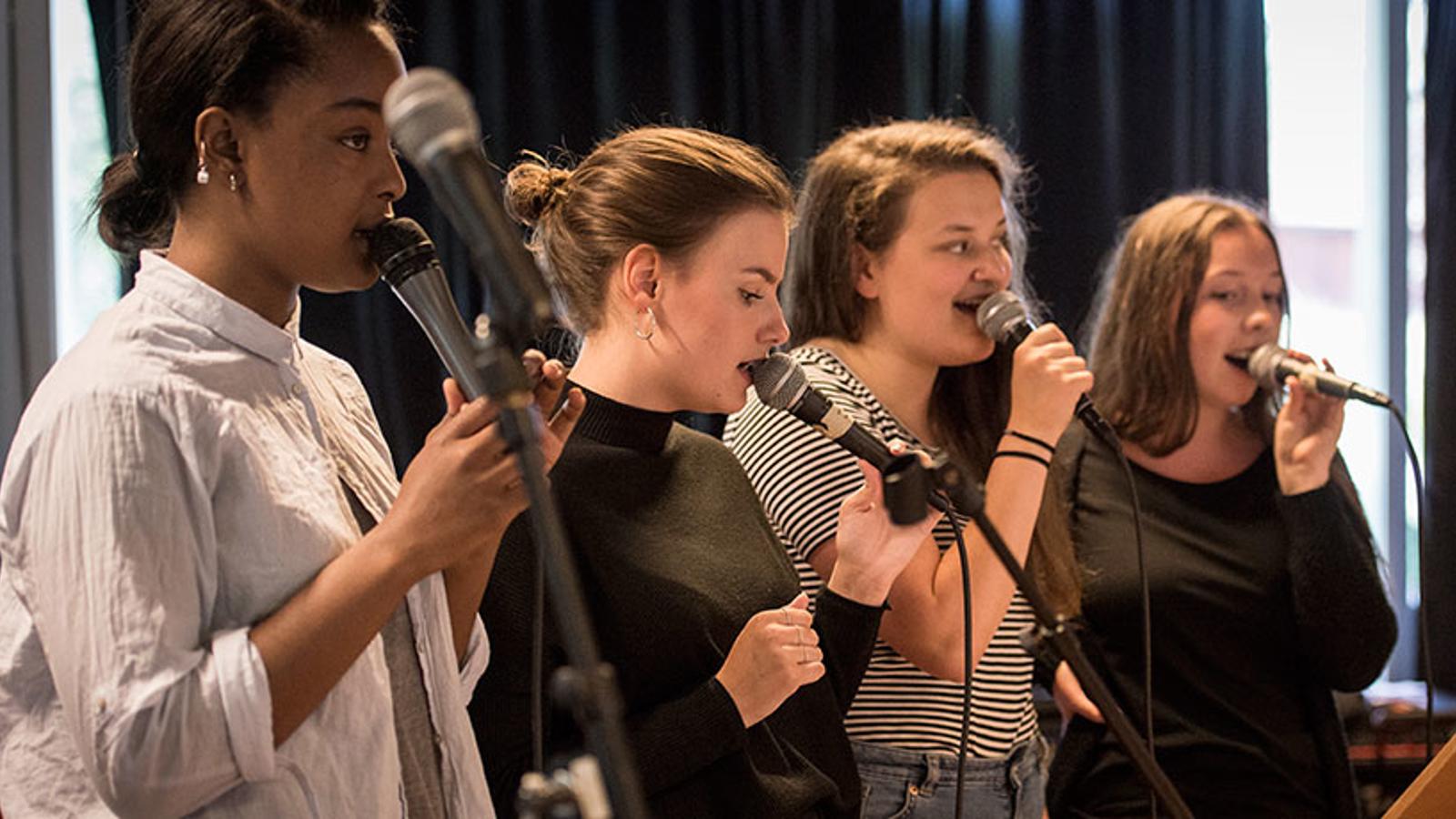 Fyra kvinnor som håller i varsin mikrofon och sjunger.