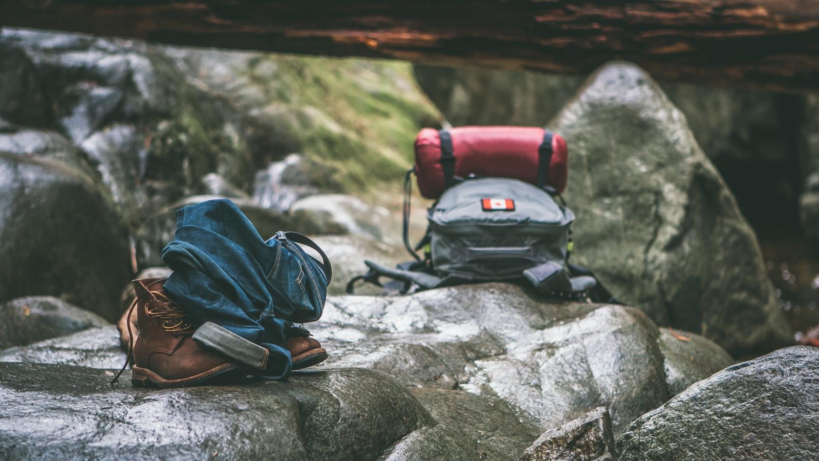 Två ryggsäckar som ligger på en stor sten ute i naturen.