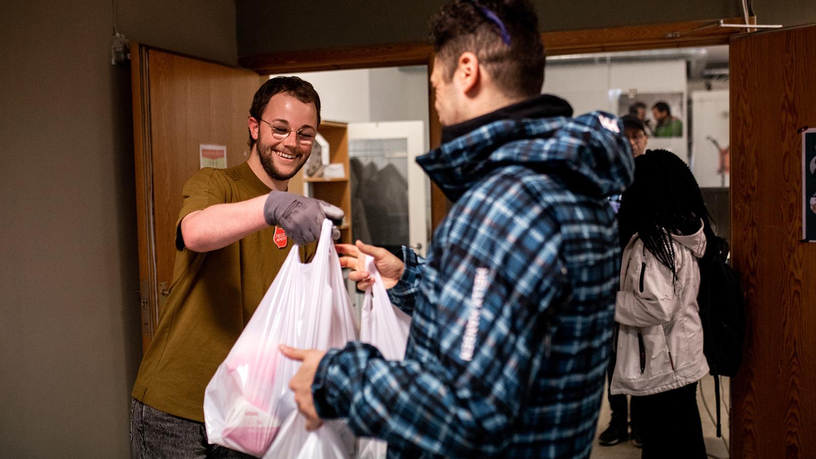 En person från Frälsningsarmén i Norge som delar ut matkassar till en man.