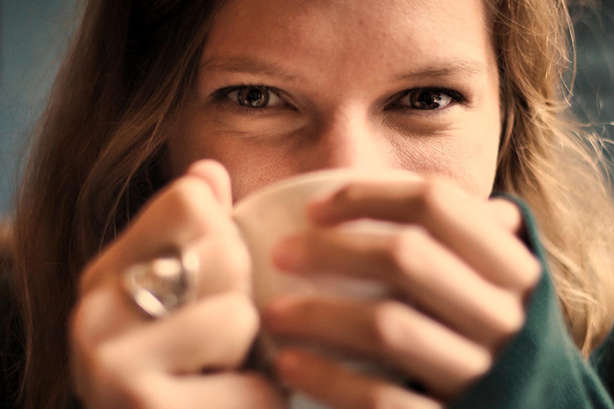 En kvinna som håller en kaffemugg för sin näsa och mun.