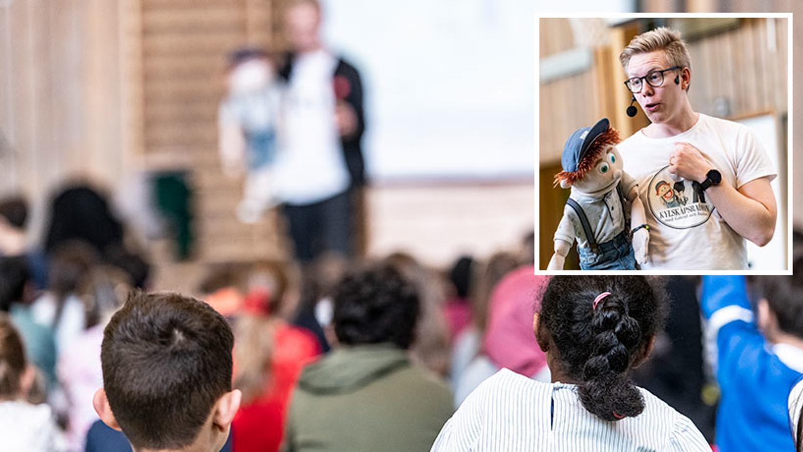 Gabriel Wahl och dockan Åsskars föreställning på en skola. I publiken sitter unga elever och lyssnar.
