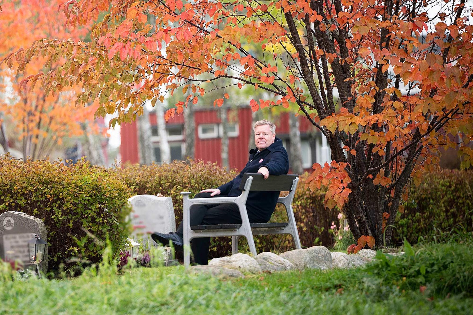 Bo Jeppsson, ledare för Frälsningsarmén i Sverige och Lettland sitter på en parkbänk framför några gravstenar på en kyrkogård. Löven på träd och buskar runtomkring har höstfärger.