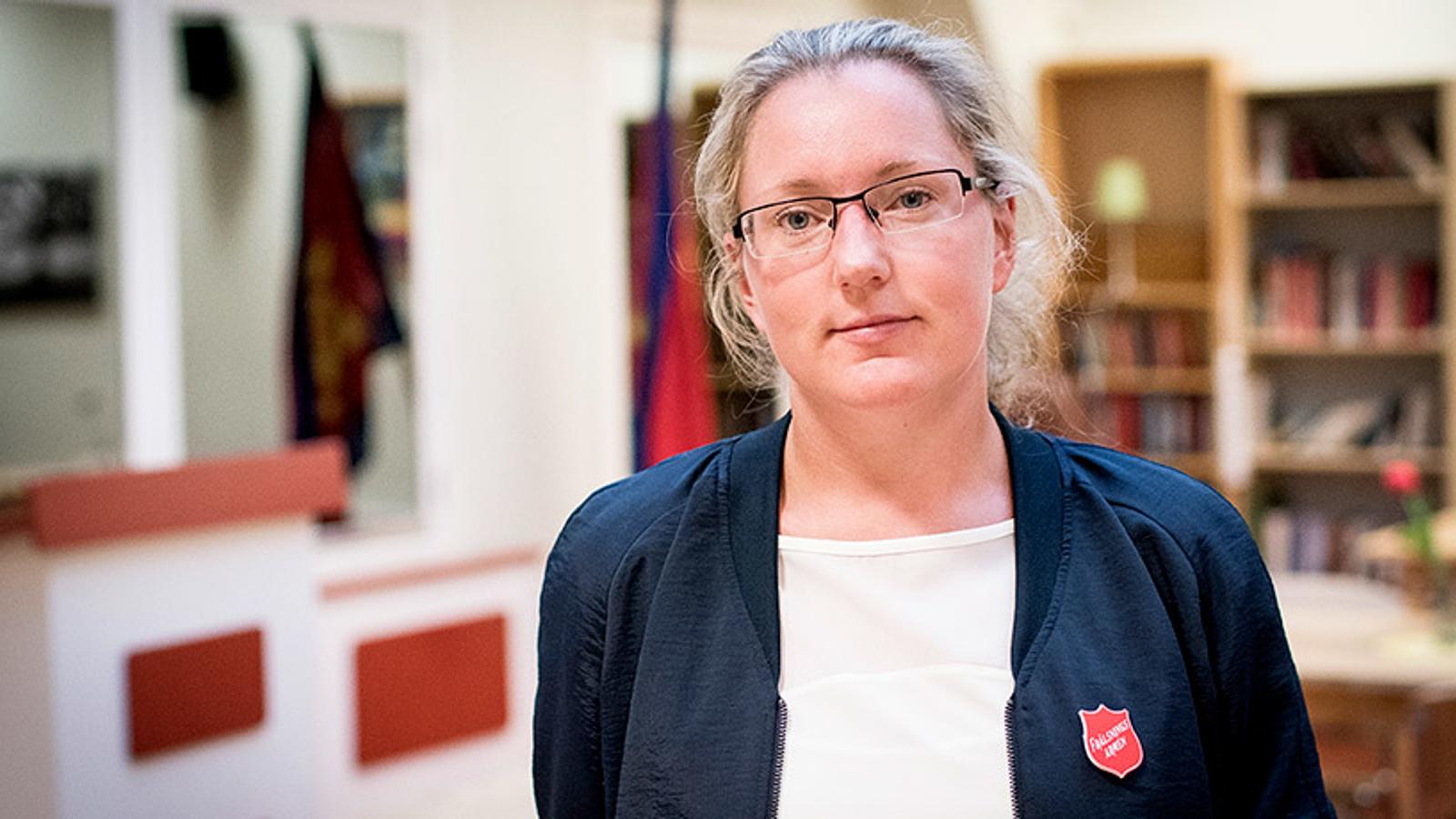 Bodil Nilsson som är verksamhetschef på Sociala centret. Hon ler mot kameran. I bakgrunden syns två bokhyllor och två röda flaggor.