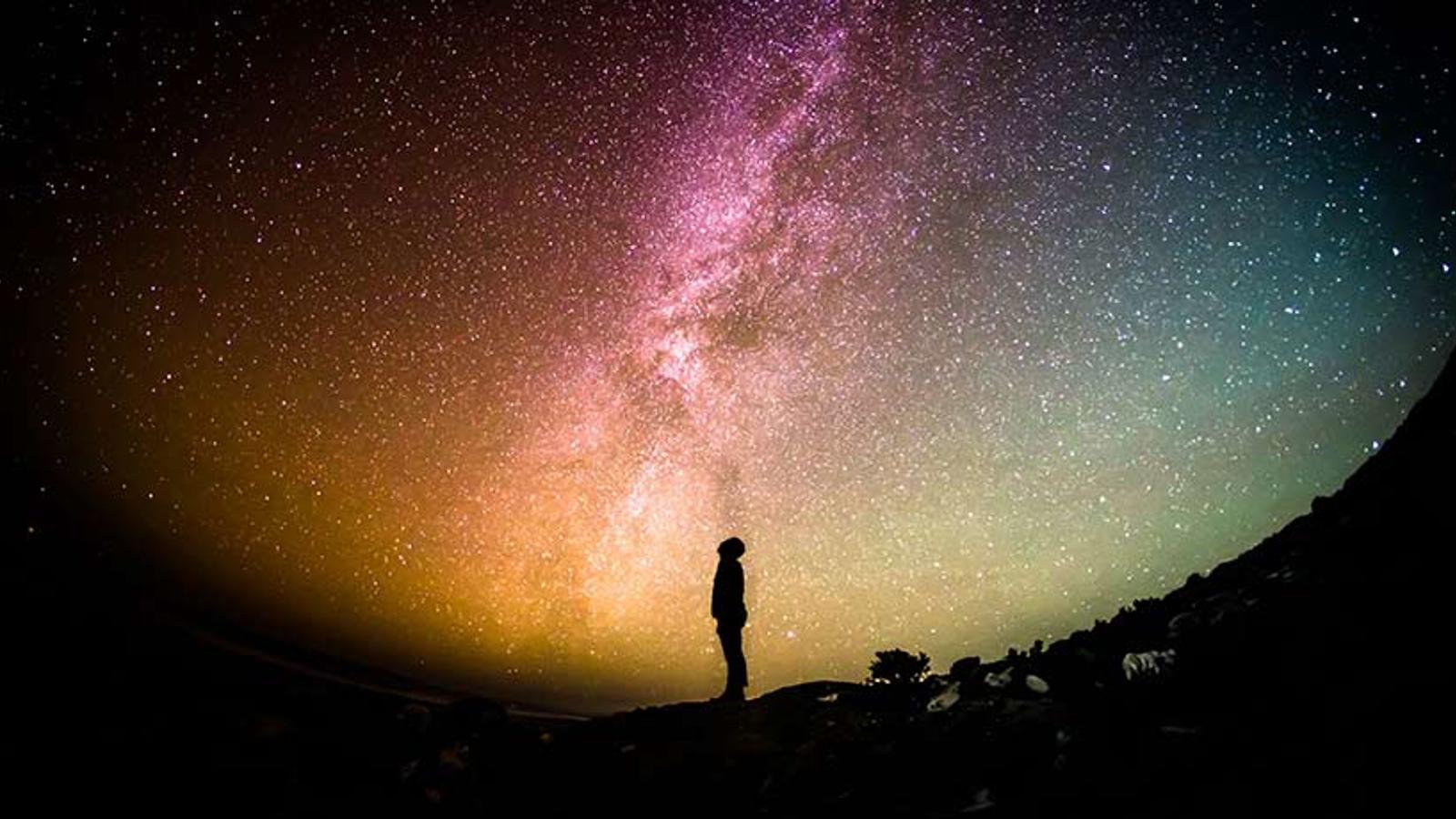 Sidoprofil av en person som tittar upp mot en mörk himmel full av stjärnor.