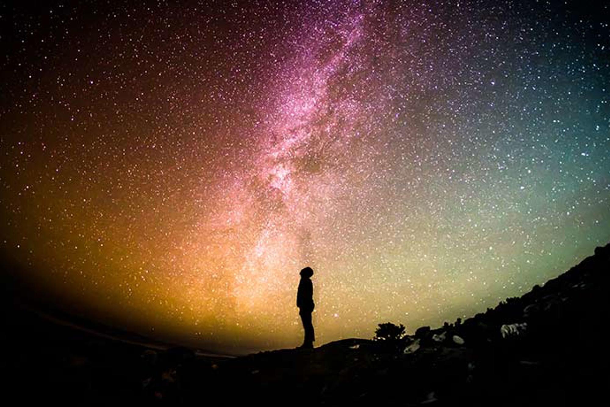 Sidoprofil av en person som tittar upp mot en mörk himmel full av stjärnor.