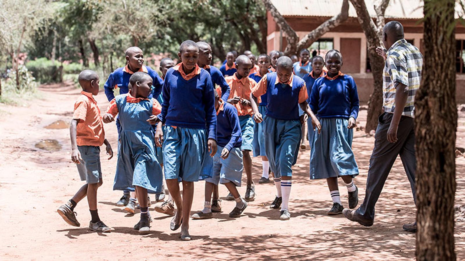 En grupp barn i skoluniform ute på gården för skolan Kyumbuni i Kenya.