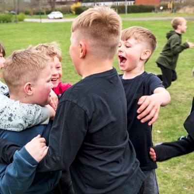 Ett gäng glada killar i 10-årsåldern kramar om varandra på fotbollsplanen.