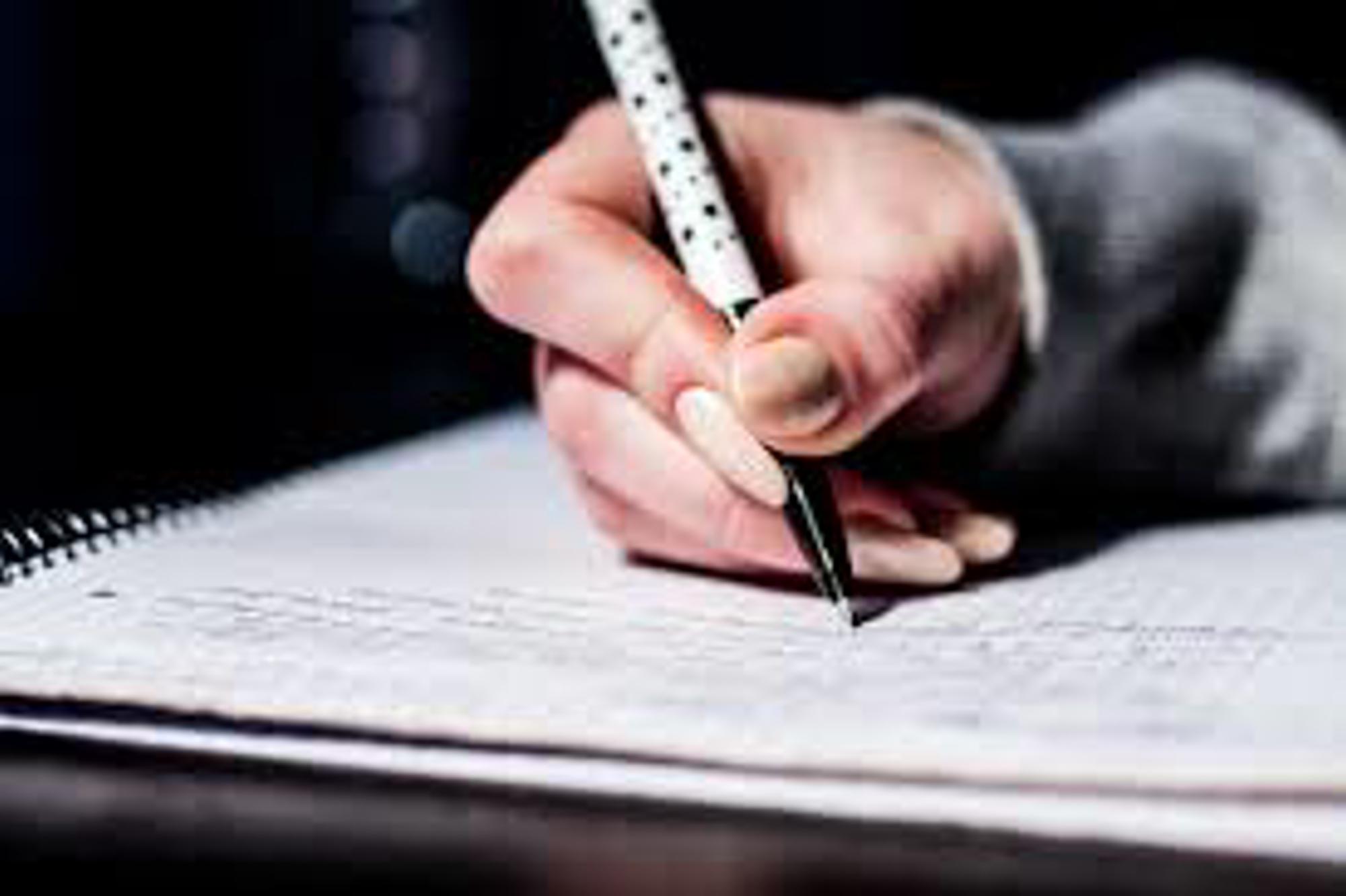 Bilden föreställer en hand som håller i en penna och vilar på ett skrivblad