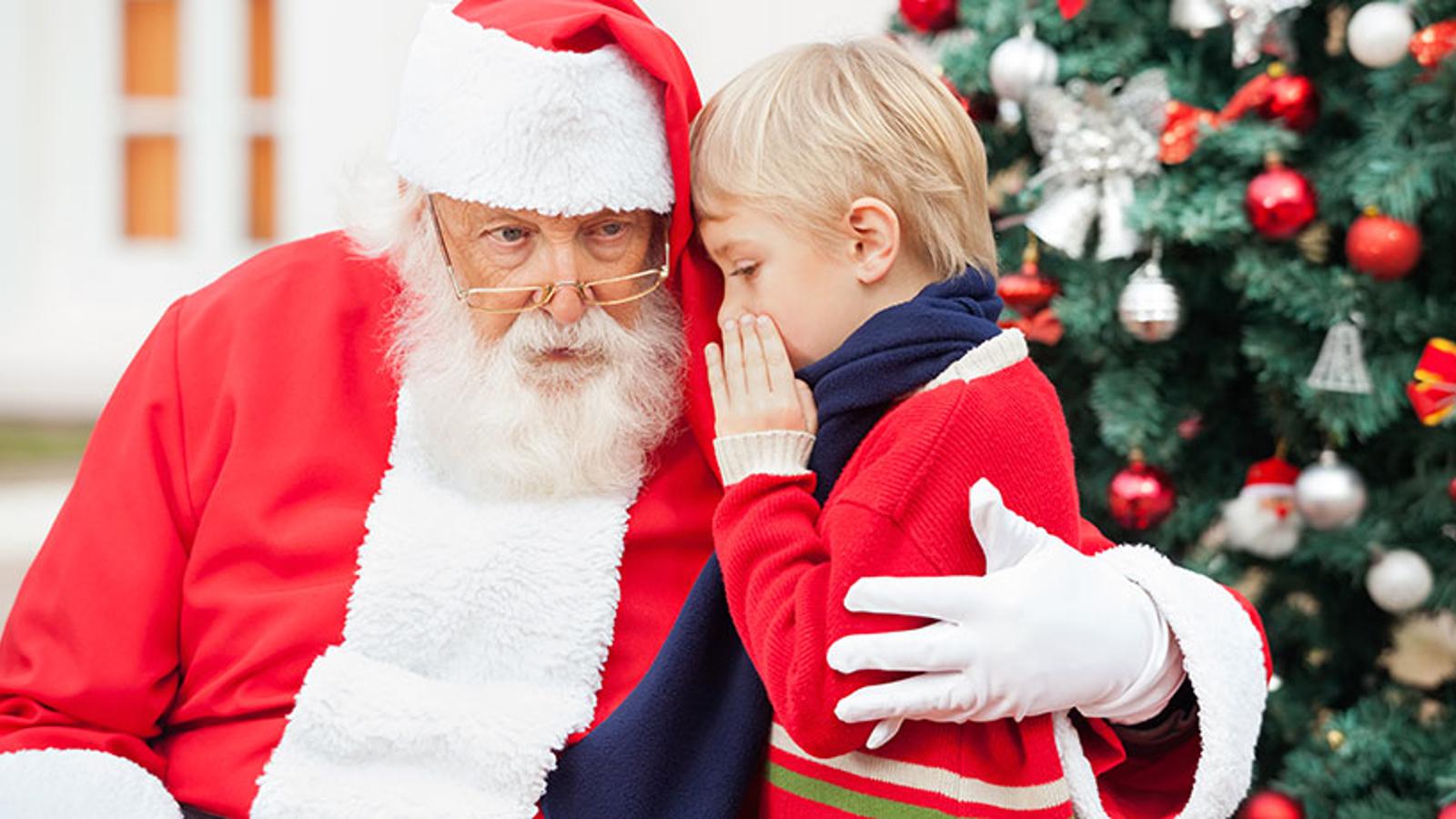 Tomten som håller om en pojke som viskar något i hans öra. Bakom dem står en klädd julgran.