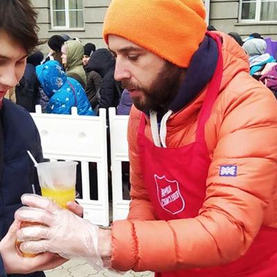 En man från Frälsningsarmén som delar ut mat och dryck till en kille i Ukraina.